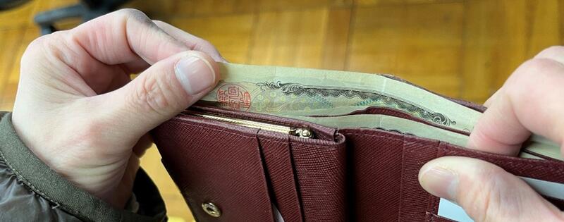 財布の中に、上下逆にしたお札が入っており、お札の左角を、指で触って券種を確認している写真