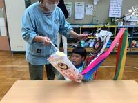 幼稚園児が小さなこいのぼりを触りながら歌を歌っている画像