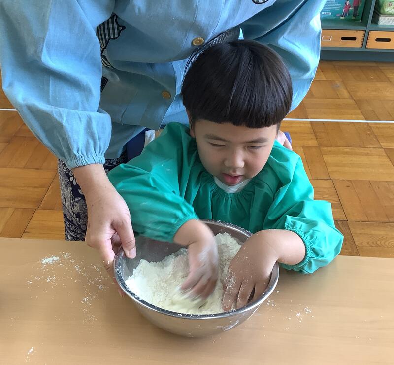 幼児がホットケーキミックスの粉と牛乳を混ぜています