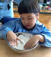 ボールに入っている粉を触る幼児