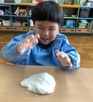 生地をテーブルに広げる幼児