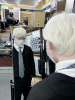 ネクタイを締めた様子を姿見で確認する生徒