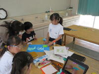 小学部児童が、折り紙にのりをつけながら聾学校児童と話している様子