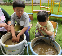 苗をバケツに植える男児と女児