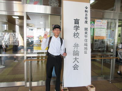 『令和８年度　関東甲信越地区　盲学校　弁論大会』の看板の前でピースをする神宮さん